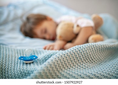 Baby boy sleeping with teddy bear and pacifier. Time to sleep concept. Focus on pacifier. Baby needs his sleep! Morning slumber. Cute little kid sleeping. Growing babies need plenty of sleep
