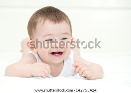 Baby boy smiling and showing his first teeth. Indoors, close up with copy space