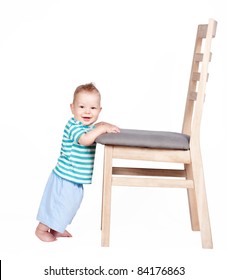 Baby Boy Standing Up Against A Chair Isolated On White Background