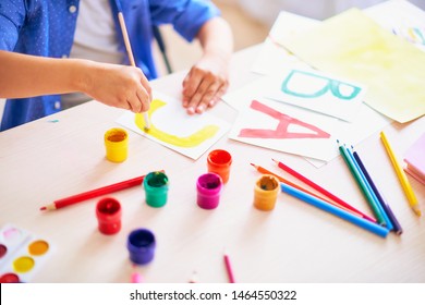 baby boy studying at home. happy child at the table with school supplies, learning the alphabet in a playful way. happy student in a bright room draws the letters with a brush and paints in gouache. - Shutterstock ID 1464550322