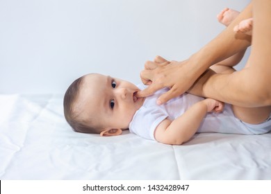 Baby boy teething pain. Little 6-month baby having teeth pains. Mother rubbing gel to her little baby boy's teeth. Medicine and health concept.