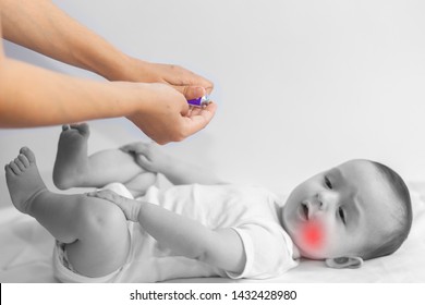 Baby Boy Teething Pain. Little 6-month Baby Having Teeth Pains. Mother Rubbing Gel To Her Little Baby Boy's Teeth. Medicine And Health Concept.