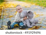 Baby boy and toy elephant having fun in fall park
