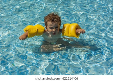 Baby Boy Wearing Yellow Water Wings Swimming In The Pool. Summertime