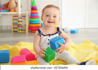 Baby with bright toy blocks in child room