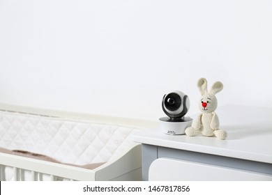 Baby Camera With Toy On Chest Of Drawers Near Crib In Room, Space For Text. Video Nanny