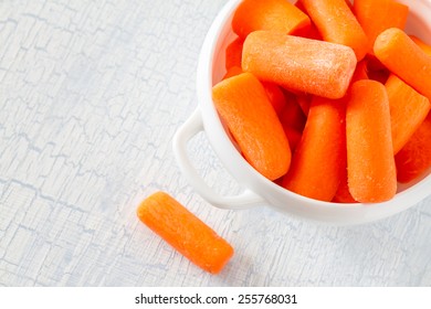 Baby Carrot Sticks In White Bowl On Light Blue Wood Background, Top View