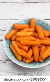 Baby Carrots In Bowl On White Wood