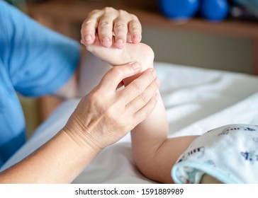 Baby with cerebral palsy having foot massage in a rehabilitation centre. Little child on therapy. Massage therapist massaging a special needs baby.