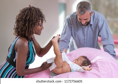 Baby Changing. Loving Mother Changing The Diaper Of Her Baby Daughter. Little Child, Girl Bedroom On Changing Table While Mum Is Looking Cheerful.