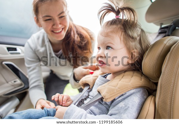 Baby in a\
child car seat. safe transportation of children. family travels.\
Mom quests his child in the car\
seat