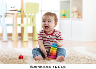 Baby child playing with educational pyramid toys at home. Little kid boy have fun indoors