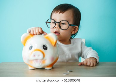 Baby Child Putting A Coin Into A Piggy Bank, Kid Saving Money For Future Concept