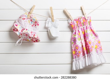 Baby clothes hanging on clothesline, on wooden background