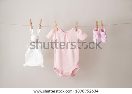 Baby clothes hanging on the rope on gray background.