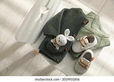 Baby Clothes, Shoes And Toy On Chair Indoors, Top View