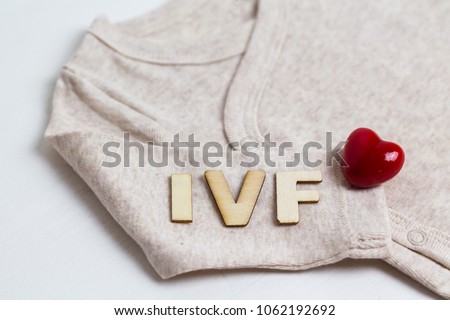 Baby clothes with test-tube and heart. Concept - IVF, in vitro fertilization. Waiting for baby, pregnant.