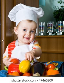 Baby In The Cook Costume In The White Hat With Vegetables