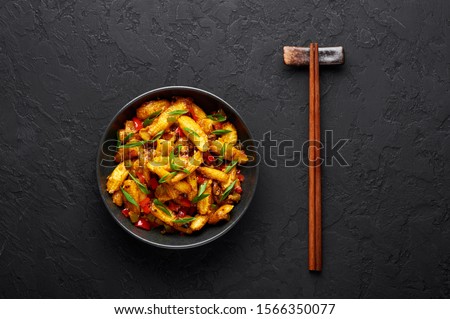 Baby Corn Manchurian dry looks like Schezwan Baby Corn in black bowl at dark slate background. Baby Corn Manchurian - is indo chinese cuisine dish with deep fried corn, bell peppers, sauce and onion.