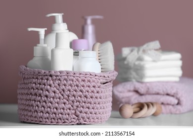 Baby Cosmetic Products And Hair Brush In Knitted Basket On White Table. Space For Text