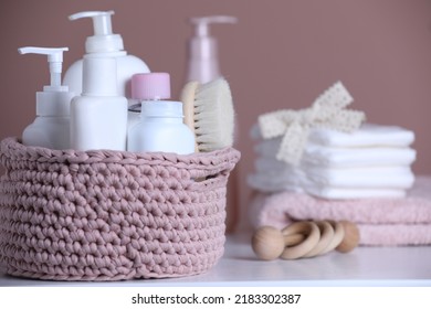 Baby Cosmetic Products And Hair Brush In Knitted Basket On White Table. Space For Text