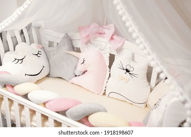 Baby Cot With A Canopy. Beautiful Bedding For A Girl. Multi-colored Pillows In The Crib. 