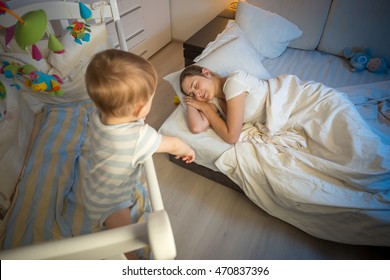 Baby In Cot Crying And Trying To Wake Up Mother That Fell Asleep