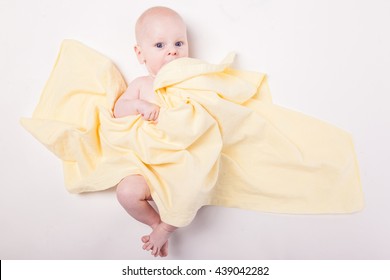 baby covered with a towel on a white background from above