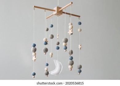 Baby crib mobile with stars, planets and moon. Kids handmade toys above the newborn crib. First baby eco-friendly toys made from felt and wood on gray background. Space for text.