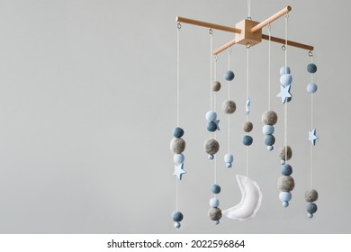 Baby crib mobile with stars, planets and moon. Kids handmade toys above the newborn crib. First baby eco-friendly toys made from felt and wood. Space for text.