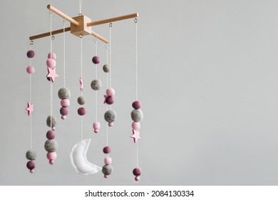 Baby crib mobile with stars, planets and moon. Kids handmade toys above the newborn crib. First baby eco-friendly toys made from felt and wood. Space for text