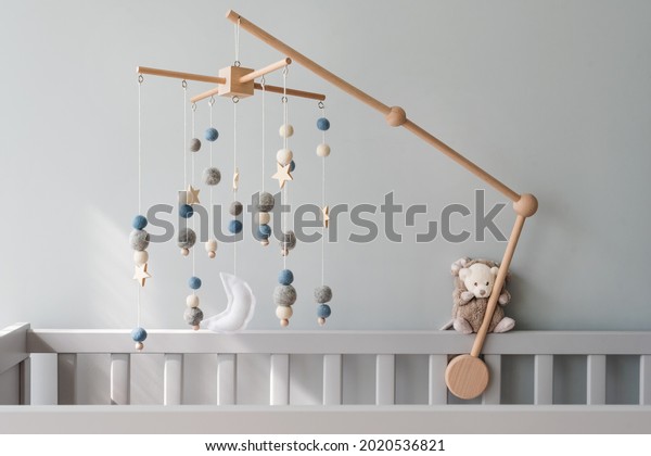 Baby crib mobile with stars,\
planets and moon. Kids handmade toys above the newborn crib. First\
baby eco-friendly toys made from felt and wood on gray\
background