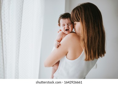 baby cries in her mother's arms - family