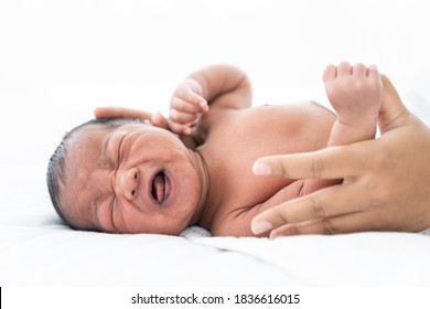 ์Newborn baby crying. African American newborn baby or infant lying on white bed while mother’s hands takes care carefully. Family, love and new life concept