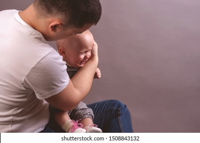 The Baby Is Crying In The Arms Of Dad.