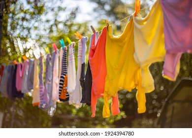 Baby cute clothes hanging on the clothesline outdoor. Child laundry hanging on line in garden on green background.Baby accessories. - Powered by Shutterstock