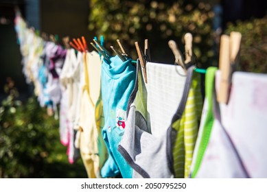 Baby cute clothes hanging on the clothesline outdoor. Child laundry hanging on line in garden.