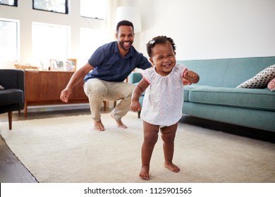 Baby Daughter Dancing With Father In Lounge At Home