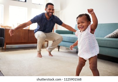 Baby Daughter Dancing With Father In Lounge At Home