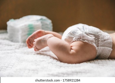 A baby in a diaper at the age of two months and a stack of diapers. How to choose baby diapers