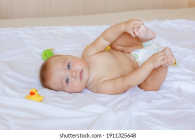 baby in a diaper lying on the bed in the bedroom with colorful toys
