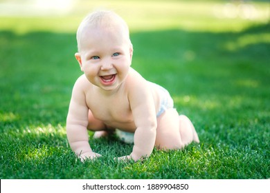 Ein Baby in einem Taucher ist auf allen Vieren auf dem grünen Gras und lächelt.