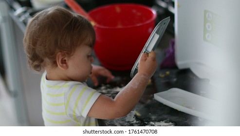 
Baby Doing A Mess At The Kitchen, Messy One Year Old Infant Playing With Flour. Toddler Child At Kitchen Cooking