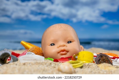 A Baby Doll Head Surrounded By Rubbish And Trash On A Beautiful Beach 