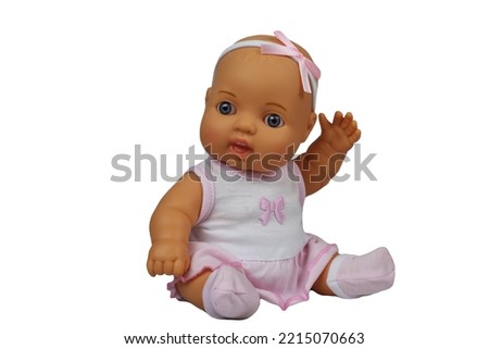 Baby doll in a pink T-shirt and a skirt with a bow on her head sits on a white background