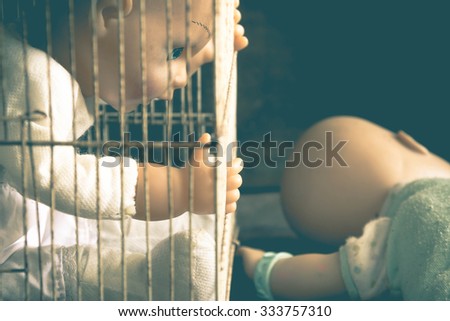Baby doll toy in cage victim emotionally,abused,kidnapped concept,Vintage filter effects