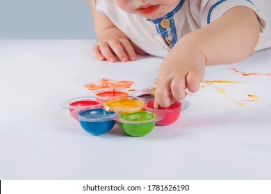 The Baby Draws On Paper With Finger Paints.