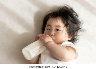 Baby drinking milk with his own baby bottle (0 years old, 8 months old, Japanese, girl)