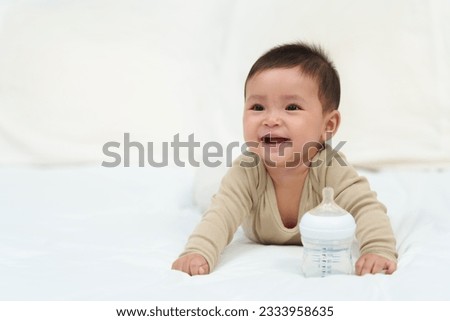 baby drinking water from bottle on a bed