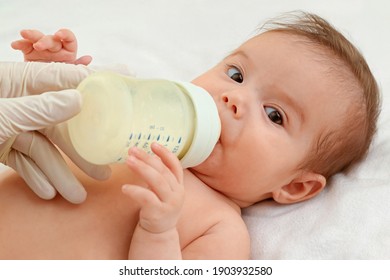 Baby Drinks From A Bottle At Home. Baby Nutrition Concept. Maternal Care For Baby.